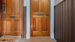 Une porte d’entrée en bois avec une fente pour le courrier et un paillasson sur lequel est écrit le mot « MAISON ».