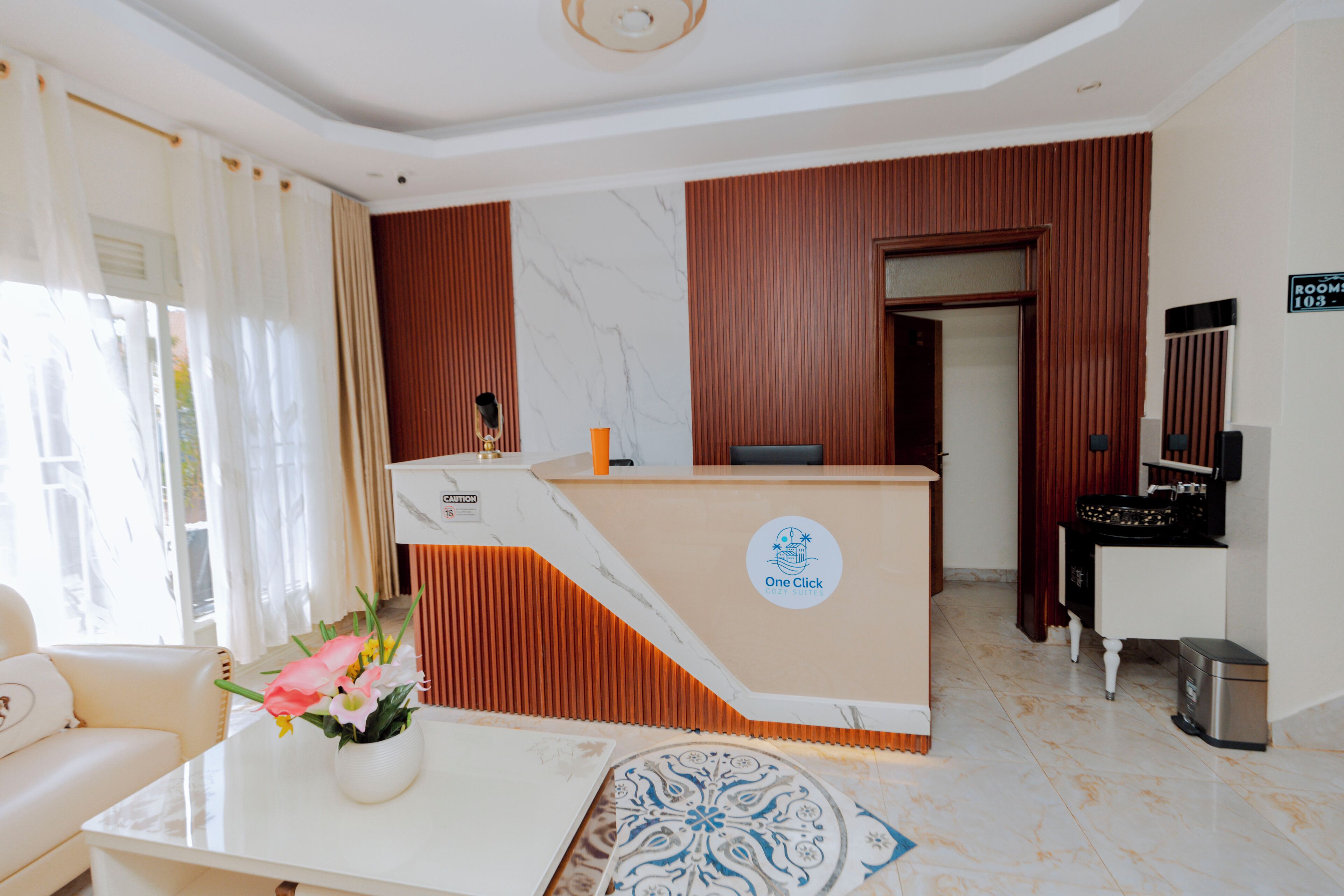 A hotel reception area with a marble reception desk, a waiting area with a sofa, and a sign indicating room 103-3.
