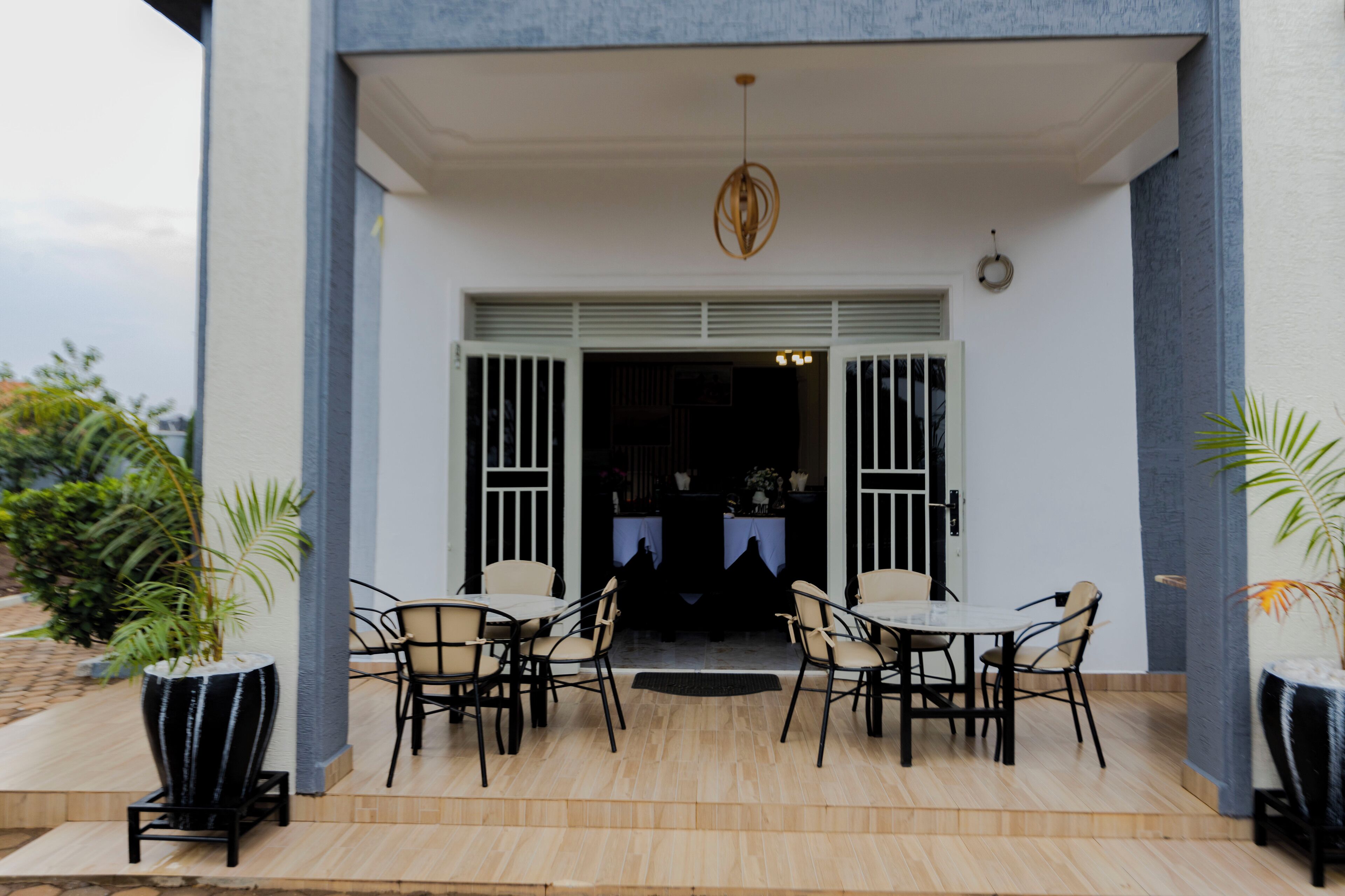 A patio with a table and chairs, a potted plant, and a hanging light fixture.