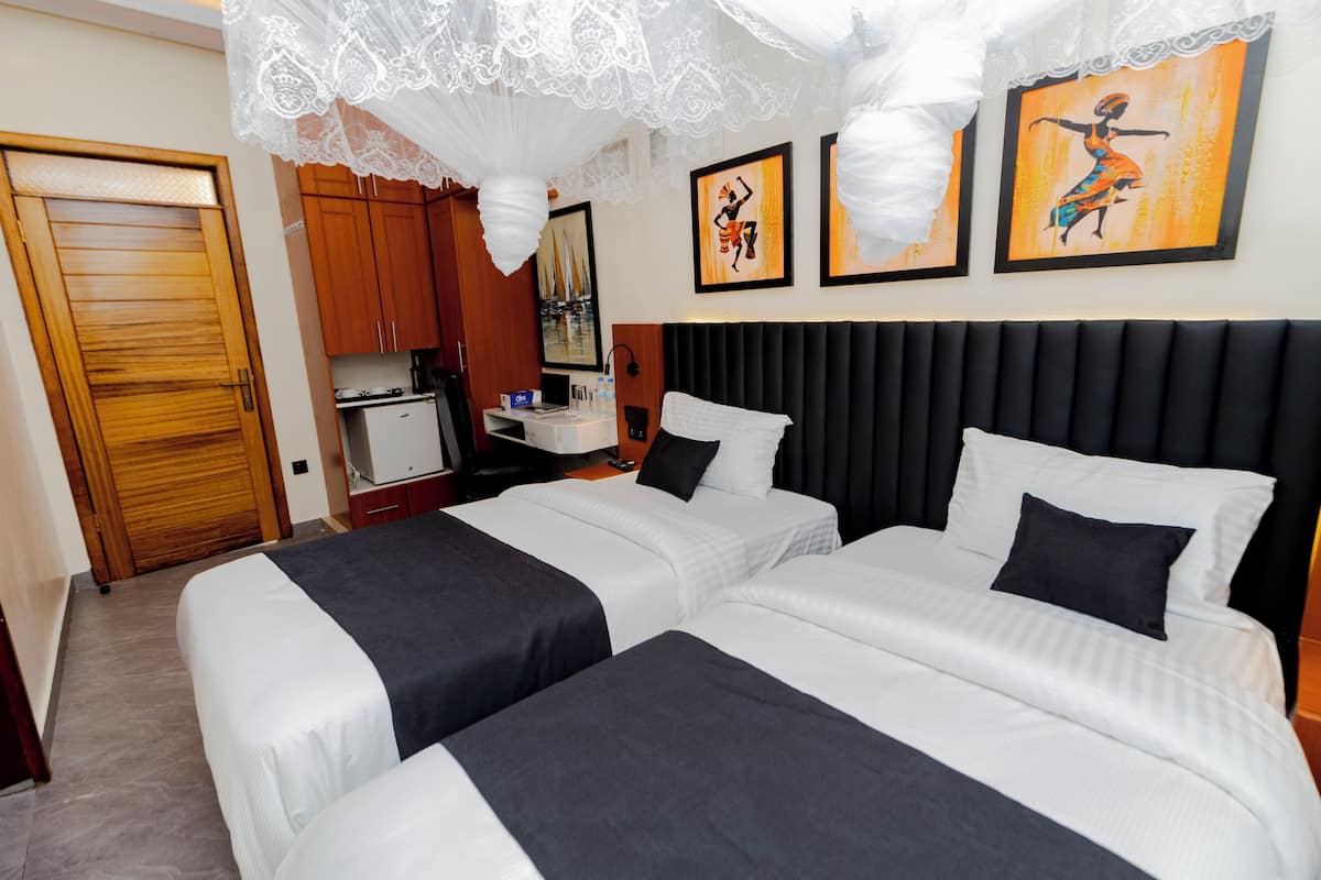 Quarto de hotel com duas camas, cozinha compacta e obras de arte na parede.