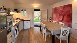 A modern kitchen with white cabinets, a dining table with chairs, and a large abstract painting on the wall. - casaVerdeMare charming detached villa Sardinia (Sardegna)