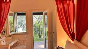 A bedroom with a bed, a desk, a chair, and a window with curtains. - casaVerdeMare charming detached villa Sardinia (Sardegna)