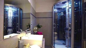 A modern bathroom with a glass-enclosed shower, a vanity with a sink, and a mirror.