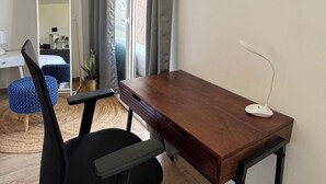 Ein modernes Zimmer mit Schreibtisch aus Holz, schwarzem Bürostuhl und Klimaanlage an der Wand.