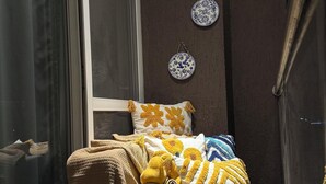 Ein gemütliches Schlafzimmer mit einem Bett, einem kleinen Tisch mit Pflanze und Tasse sowie dekorativen Tellern an der Wand.