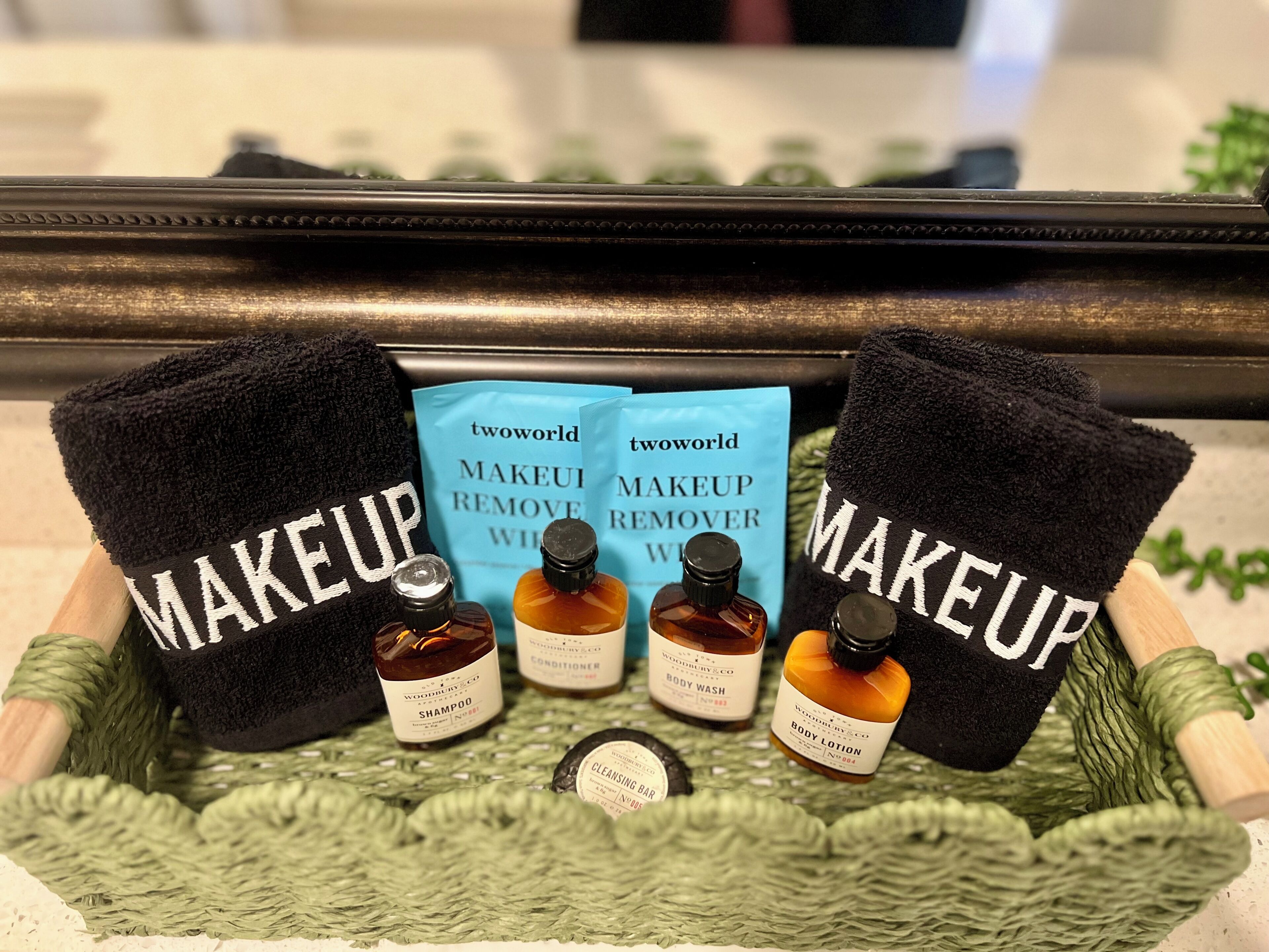 A bathroom vanity with a green towel rack holding black towels labeled "MAKEUP".