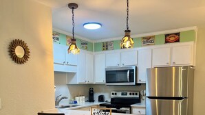 A modern kitchen with white cabinets, stainless steel appliances, and two bar stools.
