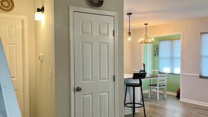 A hallway with a white door, a wall-mounted light fixture, and a ceiling light fixture.