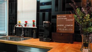 A modern kitchen with a coffee maker, a sink, and a sign that reads "Welcome to Southfork Castle, where comfort is priority." - Perfect 2-bedroom apartment with AC in nice Dallas neighborhood (Dallas)
