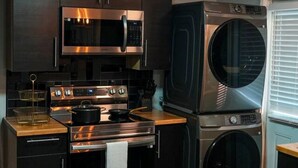 A compact kitchen with dark cabinetry, stainless steel appliances, and a built-in washer and dryer. - Perfect 2-bedroom apartment with AC in nice Dallas neighborhood (Dallas)