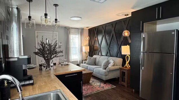 A modern kitchen with a built-in island, stainless steel appliances, pendant lighting, and a cozy seating area with a sofa and rug. - Perfect 2-bedroom apartment with AC in nice Dallas neighborhood (Dallas)
