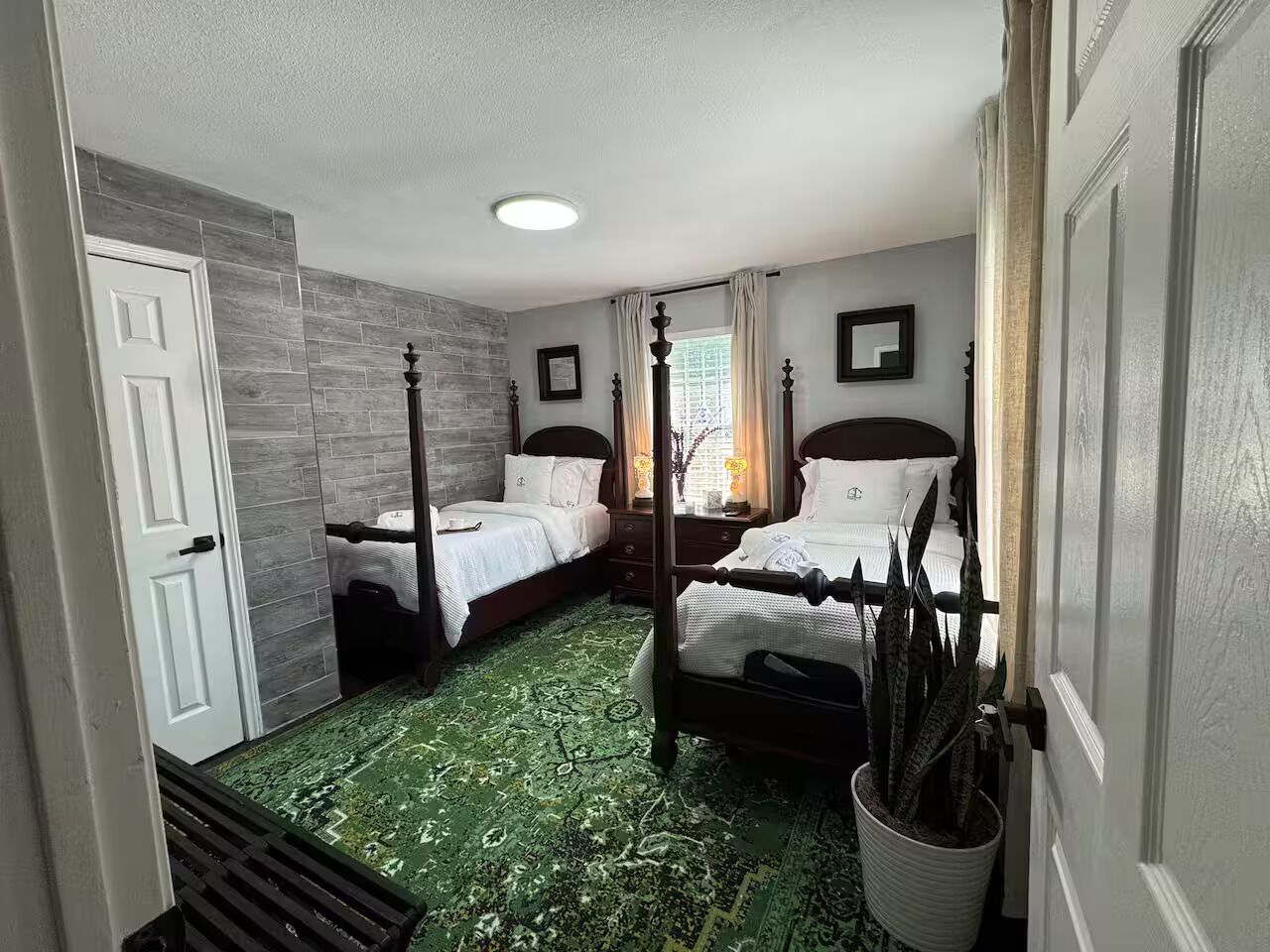 Ein Zimmer mit zwei Betten, einem gemusterten grünen Teppich und einer weißen Tür.