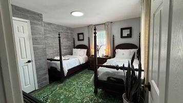 Ein Zimmer mit zwei Betten, einem gemusterten grünen Teppich und einer weißen Tür.