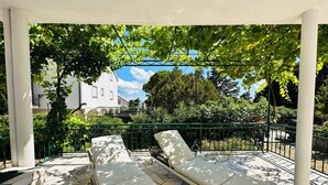 A covered outdoor seating area with two lounge chairs and a patterned tile floor. - BEACH HOUSE BOL (Bol)