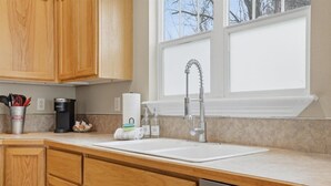 Una cocina con armarios de madera, un lavamanos blanco y una ventana sobre él.
