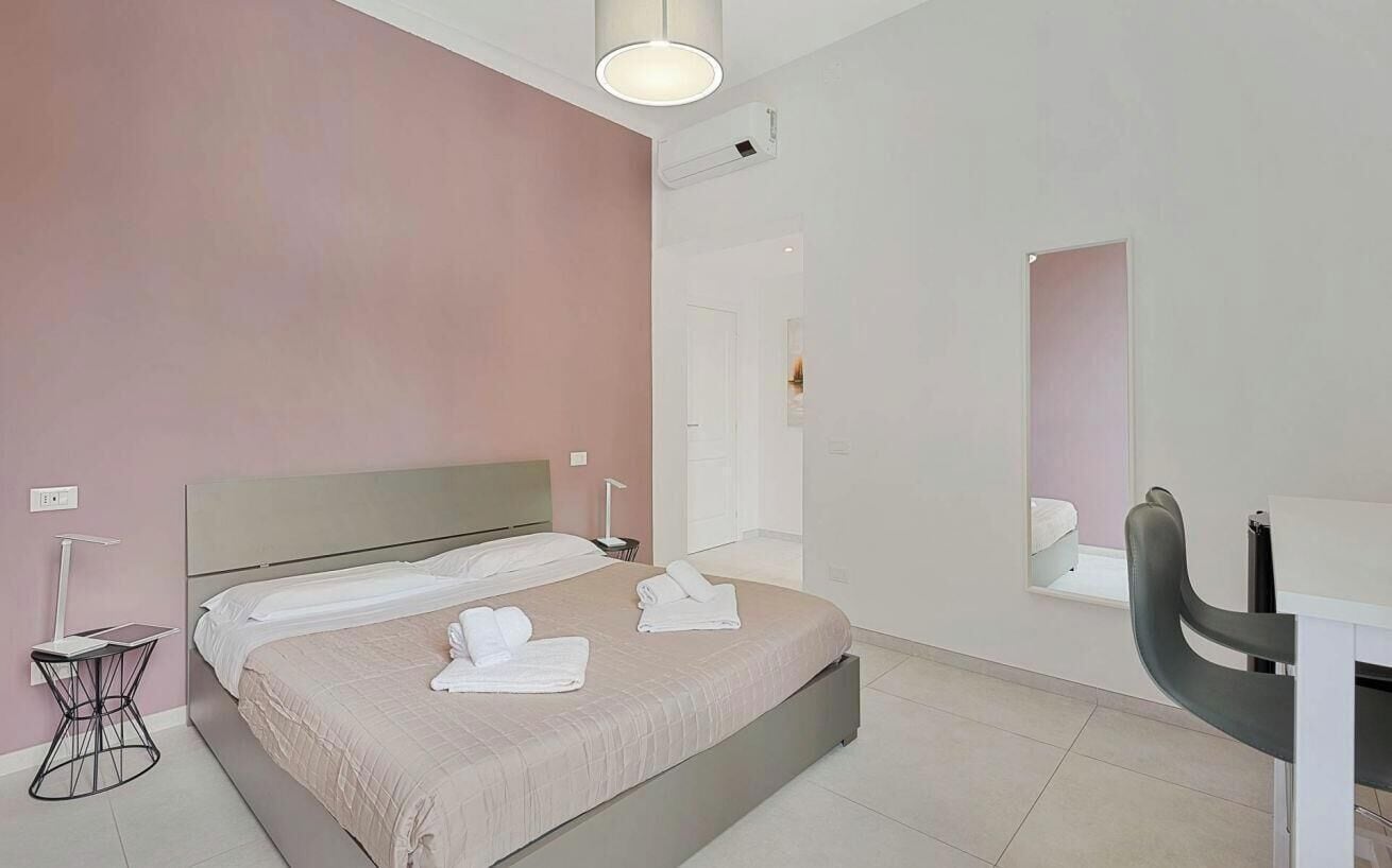 Ein modernes Hotelzimmer mit einem großen Bett, Nachttischen, einem Schreibtisch und einem Sessel.