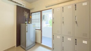 Un pasillo con taquillas identificadas de B201 a B206, un refrigerador y un equipo de aire acondicionado.