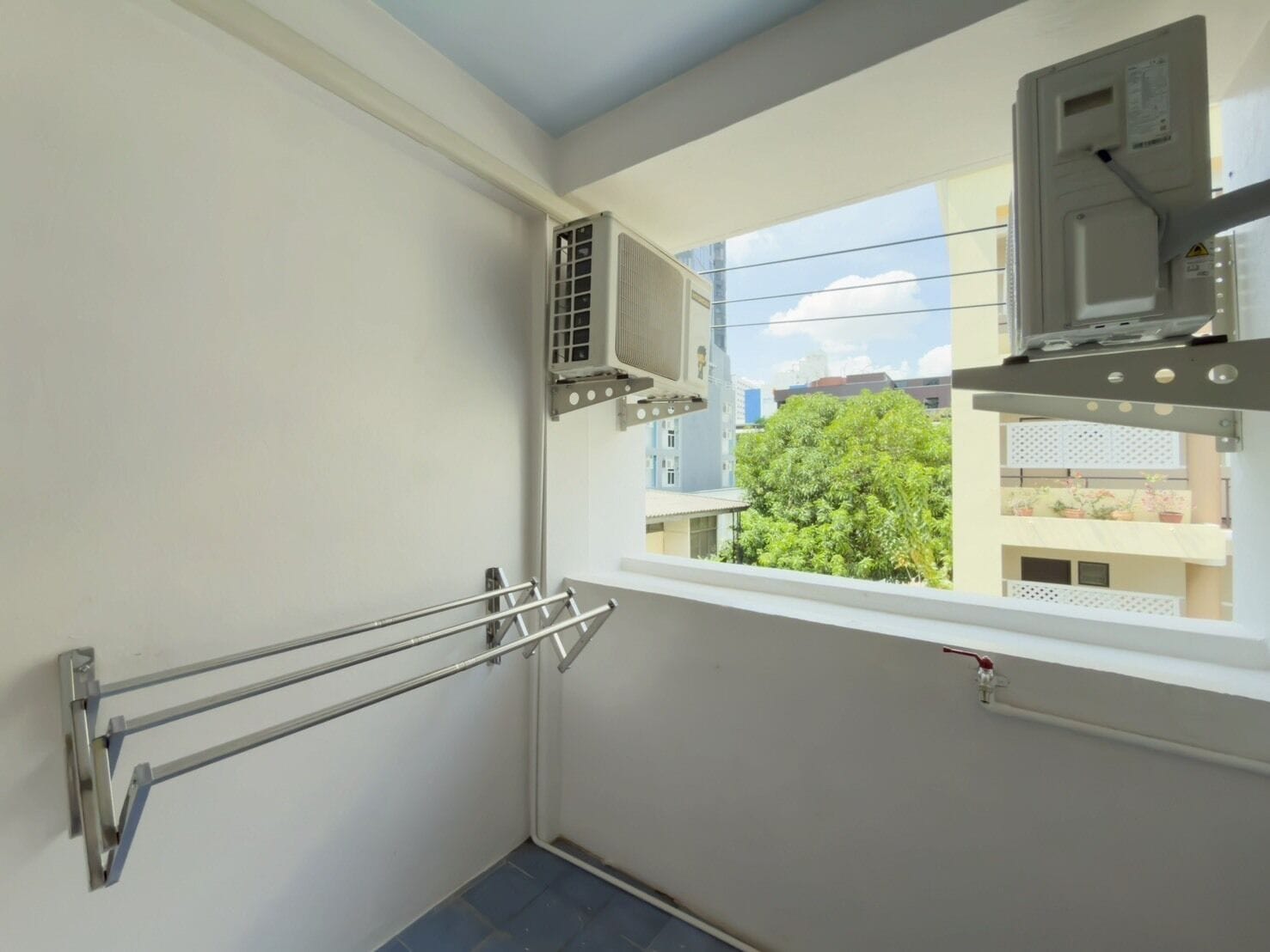 Un pequeño balcón con barandilla de metal, una ventana y un equipo de aire acondicionado.