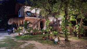 A two-story house with a balcony, surrounded by potted plants and trees. - Basilia Guest House - 1 BDR with bathroom (Santa Fe)
