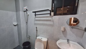 Een kleine badkamer met toilet, bidet, wastafel en spiegel.