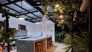 A modern kitchen with a marble island, wooden stools, and hanging plants. - Basilia Guest House - 1 BDR with bathroom (Santa Fe)