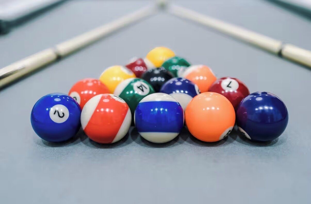 A pool table with a set of billiard balls arranged in a triangle formation.