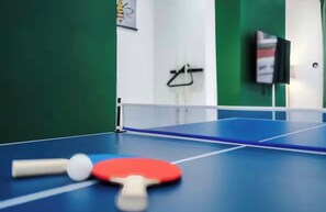 Ein Tischtennis-Tisch mit Netz, einem roten Schläger und einem weißen Ball.