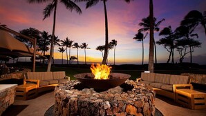 A fire pit surrounded by outdoor furniture, palm trees, and a sunset view. - Cozy 1-bedroom/living room condo with AC in charming Lahaina (Lahaina)