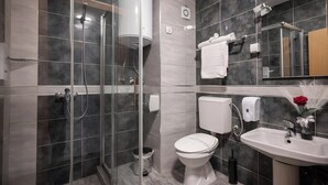 Un baño moderno con ducha envuelta en vidrio, inodoro, lavabo y espejo.