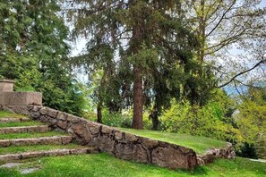 A stone staircase leading up to a grassy area with trees and a stone structure. - Enveig 1226. Cozy Mountain Apartment (Enveitg)