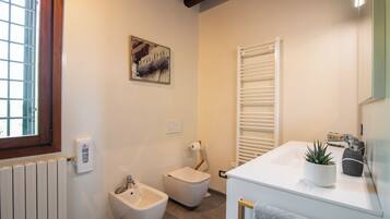 Een badkamer met een bidet, toilet, witte wastafel en een handdoekhouder.