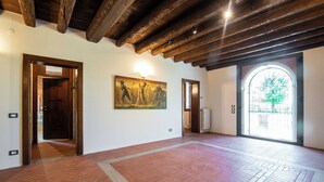 An interior with wooden beams, a herringbone floor, a painting, and a door leading outside. - Il Salice B&B Country Luxury (Due Carrare)
