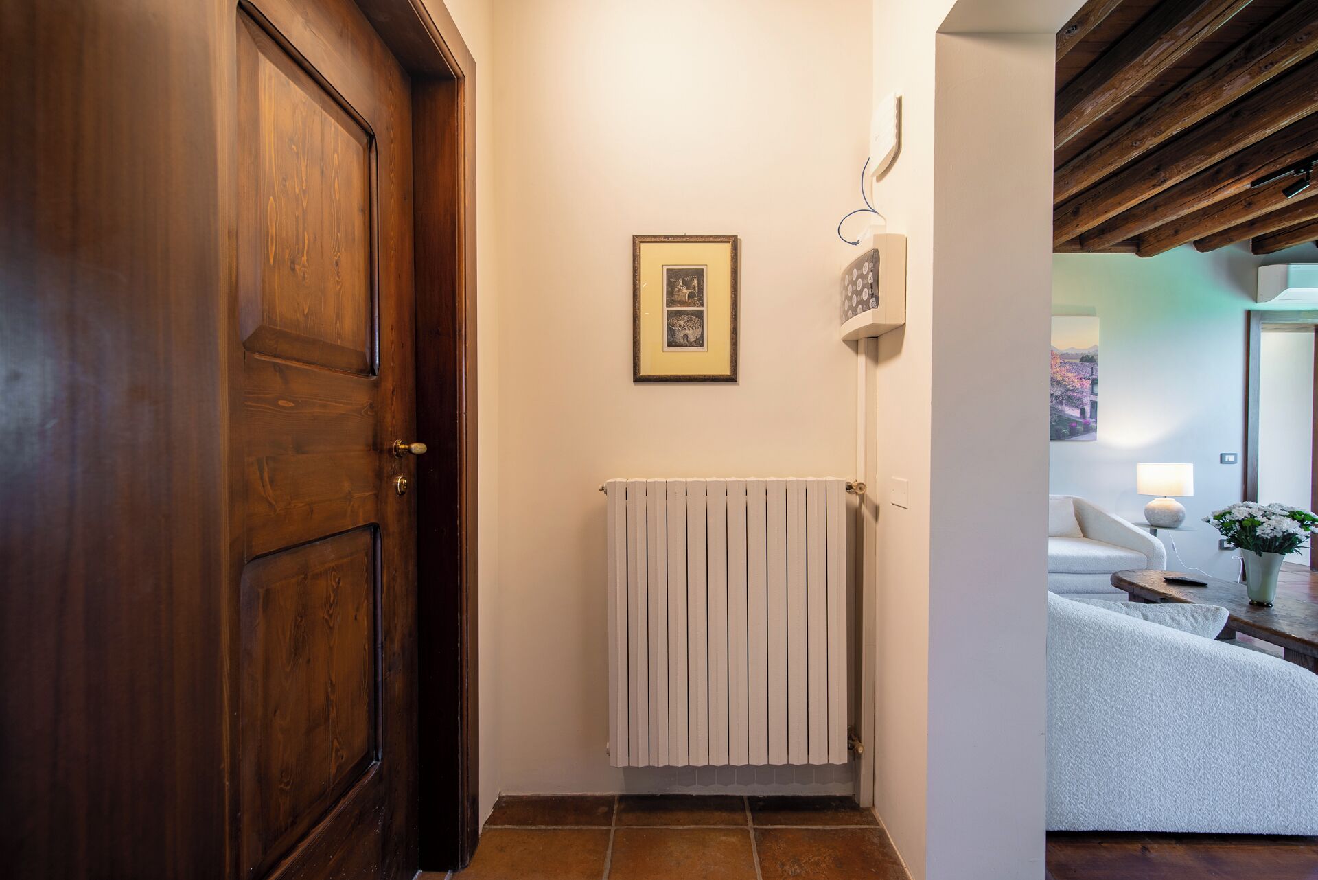 Un pasillo con una puerta de madera, un radiador y un cuadro en la pared.