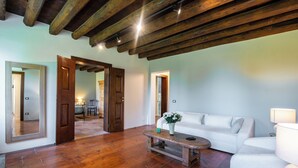 A spacious living room with wooden flooring, a white sofa, a coffee table, and a large mirror. - Il Salice B&B Country Luxury (Due Carrare)