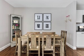 Ein Essbereich mit Holztisch und Stühlen, einem Bücherregal und gerahmten Bildern an der Wand.