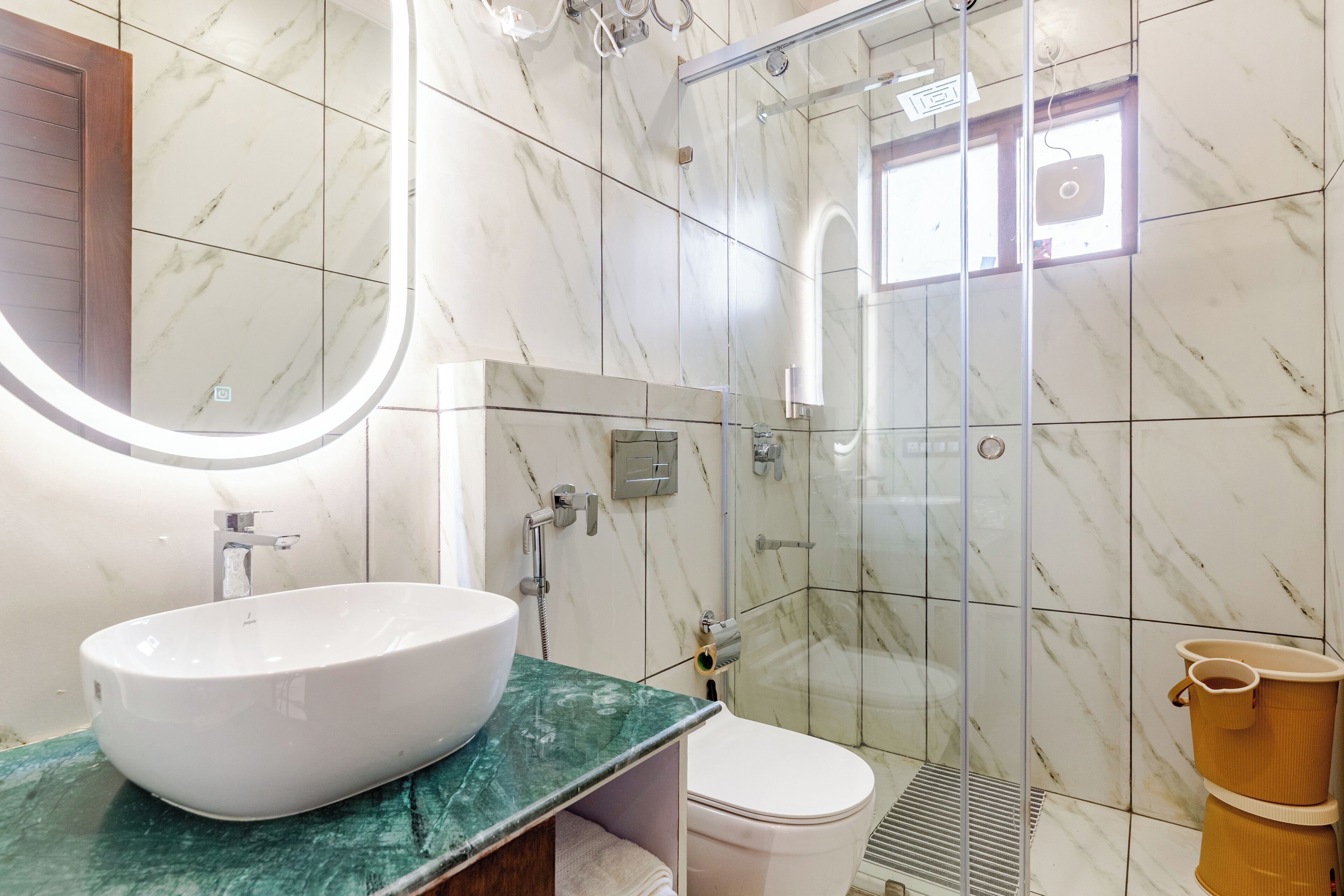 Un bany amb sòl de marbre, un rentapeus blanc i una cabina de dutxa de vidre.