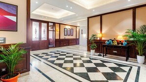 A hotel lobby with a checkered floor, wooden paneling, and a reception desk with potted plants. - The Himalayan Residency (Rampur)