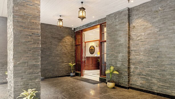 A lobby with stone walls, a wooden door, and potted plants. - The Himalayan Residency (Rampur)