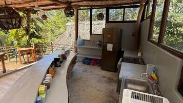 Een koelkast, een oven, een kookplaat, kookgerei, borden en bestek