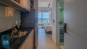 Una cocina moderna con horno empotrado, un comedor con mesa y sillas, y un dormitorio con cama y vistas al océano.