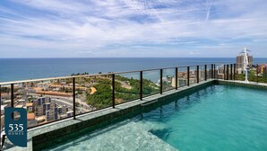 Una piscina en la azotea con vistas a la ciudad, rodeada por una barandilla de cristal.