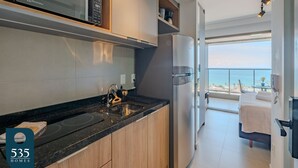 Una cocina moderna con microondas integrado, refrigerador de acero inoxidable y encimera negra.
