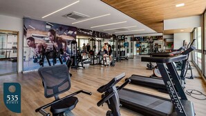 Un gimnasio con cintas de correr, bicicletas estáticas y máquinas de pesas.
