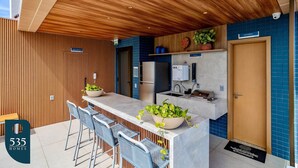 Una cocina moderna con techo de madera, una barra con sillas y un cartel para el baño.