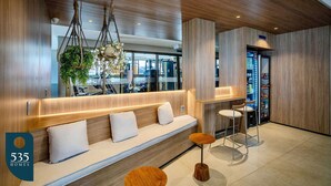 Un interior moderno con un banco de madera, dos taburetes y una máquina expendedora.