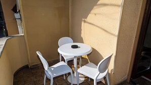 Un pequeño patio exterior con una mesa redonda y cuatro sillas blancas.