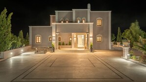 A large, modern building with a symmetrical facade, multiple windows, and a well-lit entrance. - Leon Villa (Santorini)