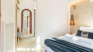 A modern hotel room with a neatly made bed, a walk-in closet, and a large mirror. - Leon Villa (Santorini)