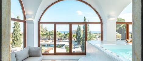 Una habitación amplia con un gran ventanal arqueado, una zona de estar acogedora y un jacuzzi privado.