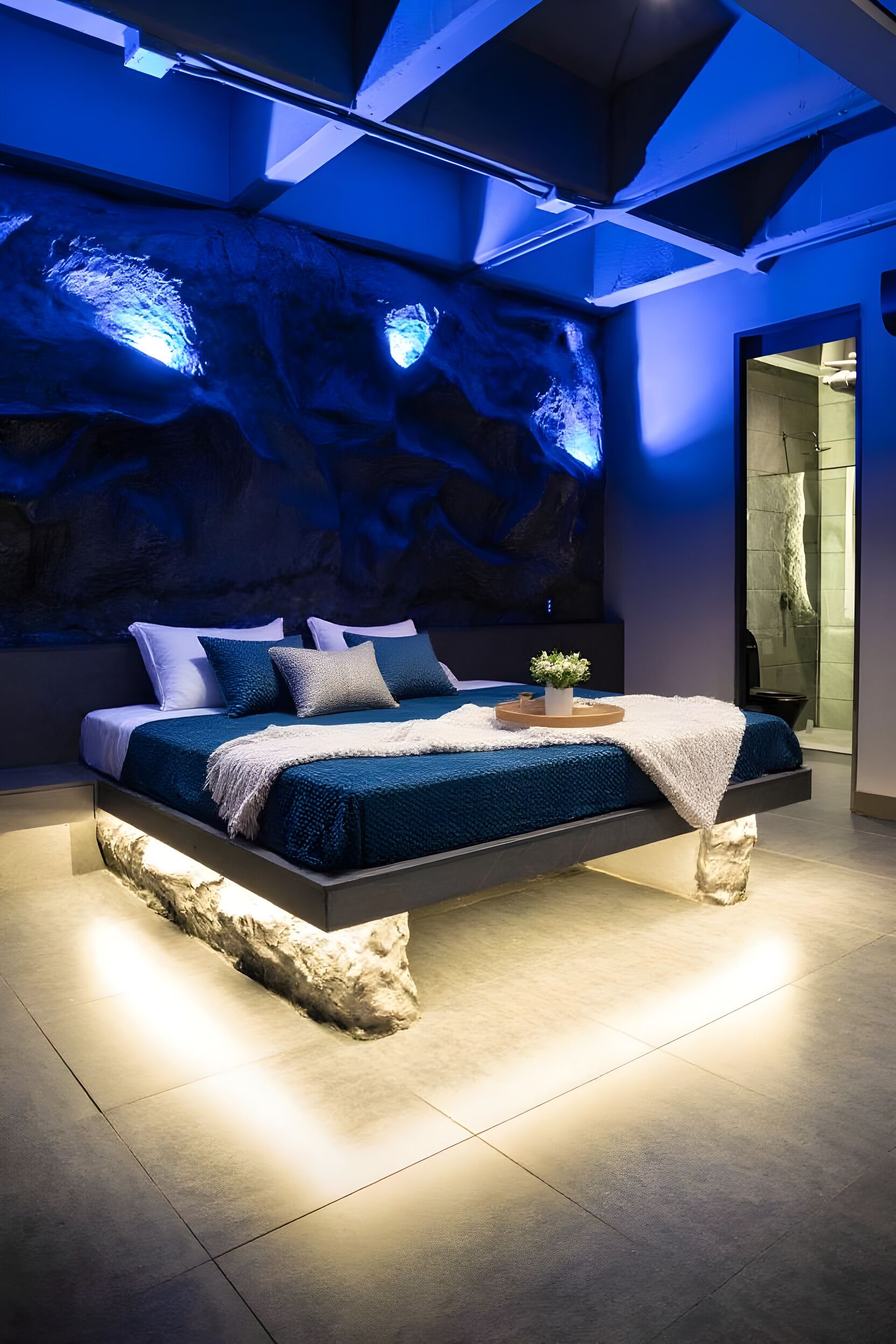 Une chambre moderne avec un grand lit, un téléviseur fixé au mur et un socle original qui ressemble à un rocher.